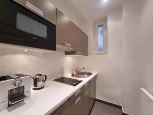 una cocina blanca con fregadero y microondas en Appartement Commandant André, en Cannes