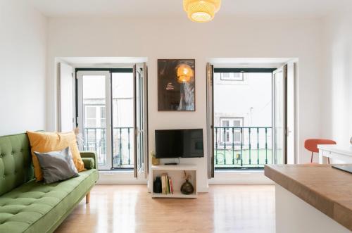 a living room with a green couch and two windows at Severa Apartments in Lisbon