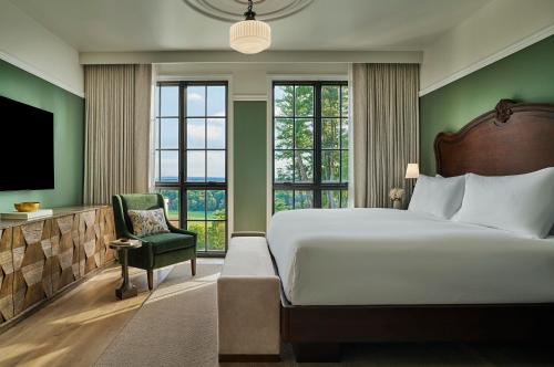 a bedroom with a bed and a chair and windows at Pendry Natirar in Peapack