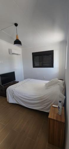 a bedroom with a white bed and a wooden table at The Yerbal Thermal House in Termas de Guaviyú
