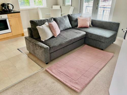 a living room with a gray couch with pink pillows at Quiet 2 Bedroom Apartment in Headington, Close to Oxford Hospitals & Brookes University in Oxford