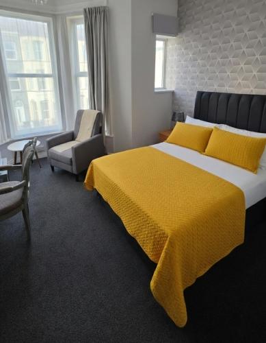 a bedroom with a large bed with a yellow blanket at Sunset Suites in Blackpool