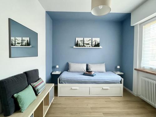 a bedroom with blue walls and a bed and a couch at The Cozy Peak - 360 Dolomites View in Agordo