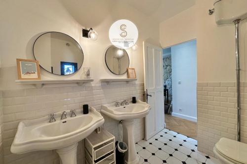 a white bathroom with two sinks and a mirror at L'Orangeraie Arles in Arles