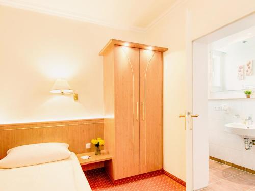 a bedroom with a bed and a sink and a cabinet at Hotel Kriemhild am Hirschgarten in Munich