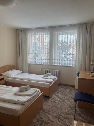 a hotel room with three beds and a window at Hotel Europa in Elblag