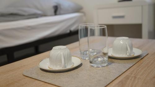 a wooden table with two glasses and plates on it at Zentrales Apartment Lichtenfels in Lichtenfels