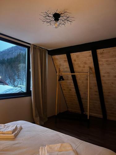 a bedroom with a bed and a window with a view at A-frame Boema in Cîmpu lui Neag