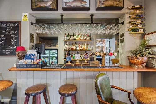 a bar with two stools and a counter with alcohol at Flower Pot Hotel in Henley on Thames
