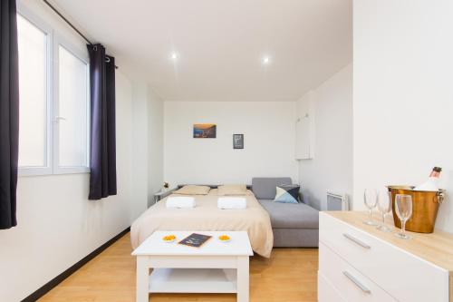 a white bedroom with a bed and a table at Monaco Border - Coquet et Authentique - FM in Beausoleil