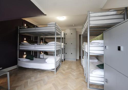 a room with three bunk beds with white sheets at Revolver Edinburgh in Edinburgh