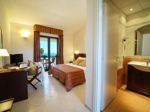 a bedroom with a bed and a bathroom with a sink at Fruit Village Tropea Baia della Rocchetta Soft all Inclusive in Conidoni