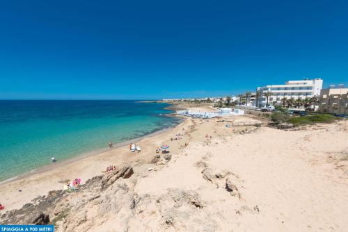 a beach with people on the sand and the ocean at Residence Salento Fronte Mare - Coste del Sud it in Torre San Giovanni Ugento