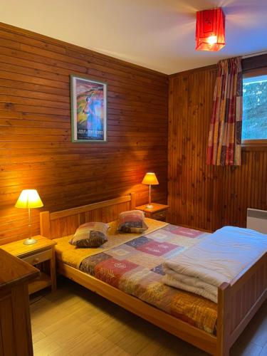 ein Schlafzimmer mit einem großen Bett in einer Holzwand in der Unterkunft Chalet L'Eider in Bolquere
