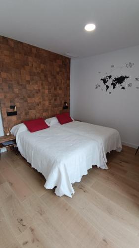 a bedroom with a large white bed with red pillows at Casa Huidobro Valle II in Sardón de los Frailes