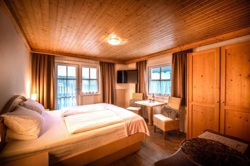 a bedroom with a bed and a desk and windows at Pension Kuntschner in Mittersill