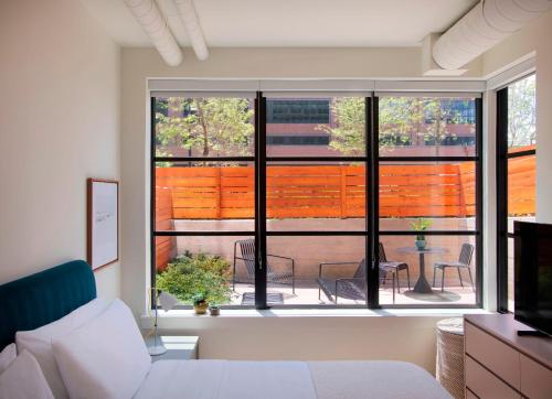 a bedroom with a bed and a window with a patio at Roost Baltimore in Baltimore