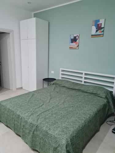 a bedroom with a bed with a green blanket at Le 2TORRI in Falconara Marittima