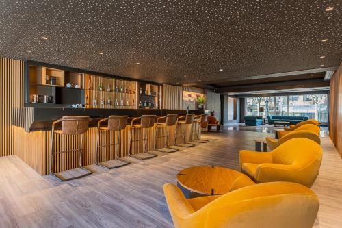 a restaurant with yellow chairs and a bar at HF Tuela Porto in Porto
