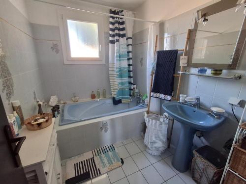 a bathroom with a blue tub and a sink at Grande Chambre double in Sérignan