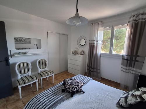 a bedroom with a bed and two chairs and a window at Grande Chambre double in Sérignan