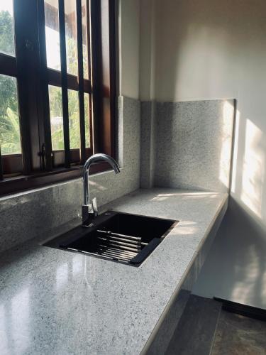 a kitchen counter with a sink and a window at RailNest in Talpe