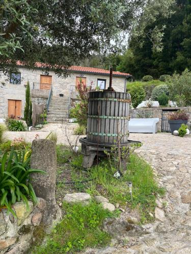 a garden with a wooden barrel in front of a house at Quinta da Lembrança in Arcos de Valdevez