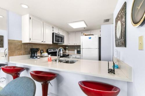 a kitchen with red stools and a white counter top at One Seagrove Place 1505 in Santa Rosa Beach