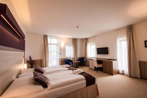 a hotel room with a large bed and a desk at Hotel Golf Resort Olomouc in Dolany