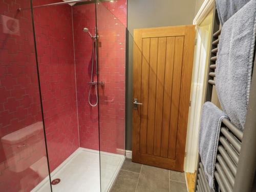 a bathroom with a glass shower with red tiles at Otter's Rest in Droitwich