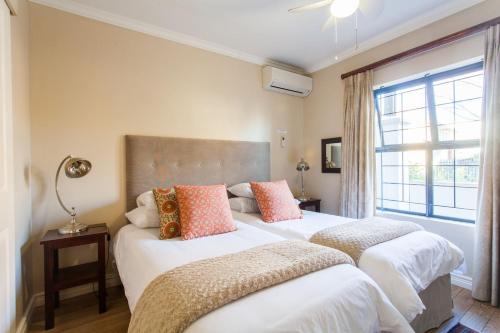 two beds in a room with a window at Vino Self Catering Apartment in Stellenbosch