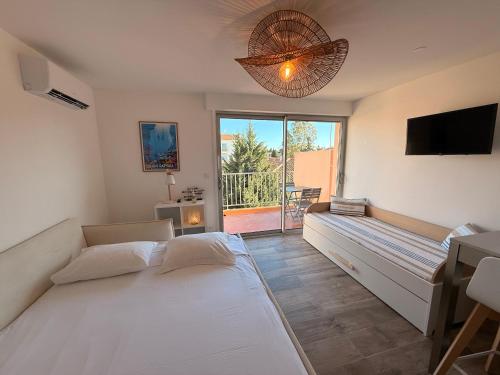 a bedroom with a bed and a television and a balcony at Le Petit Bleu Studio - Boulouris in Saint-Raphaël