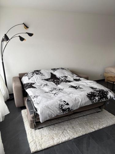 a bed with a black and white comforter in a bedroom at Studio rénové Ovronnaz chalet Orion in Ovronnaz
