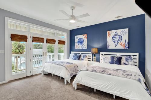 two beds in a bedroom with blue walls and windows at Front Porch Lounge in Tybee Island