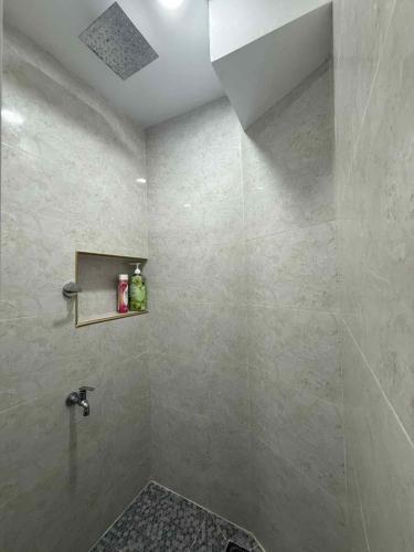 a bathroom with a shower with a tiled wall at JMATS Homestay in Dipolog