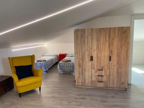 a room with a yellow chair and a wooden cabinet at Dimora Coacci in Grottammare