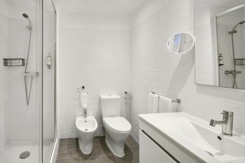 a white bathroom with a toilet and a sink at Monte Gordo Prestige Apartments in Monte Gordo