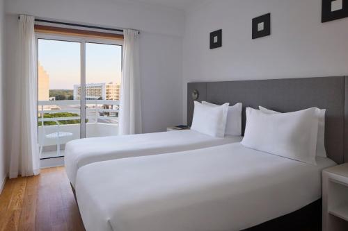 a bedroom with two beds and a large window at Monte Gordo Prestige Apartments in Monte Gordo