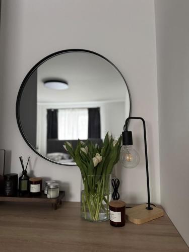 a vase of flowers on a table with a mirror at Central Apartment in Jelgava