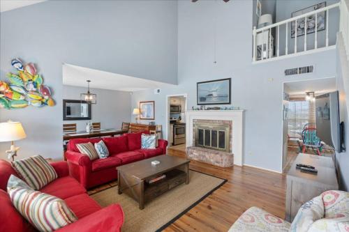 a living room with a red couch and a fireplace at Sunset Daze by Youngs Suncoast in Gulf Shores
