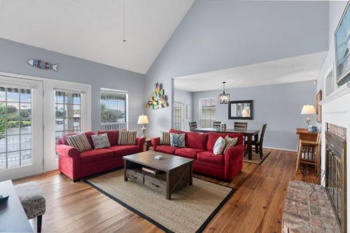 a living room with red couches and a table at Sunset Daze by Youngs Suncoast in Gulf Shores