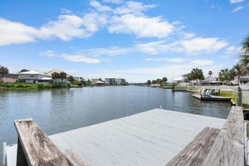 a river with a wooden dock and houses at Sunset Daze by Youngs Suncoast in Gulf Shores