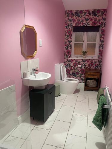 a pink bathroom with a sink and a toilet at Old Swan Cottage in Great Massingham