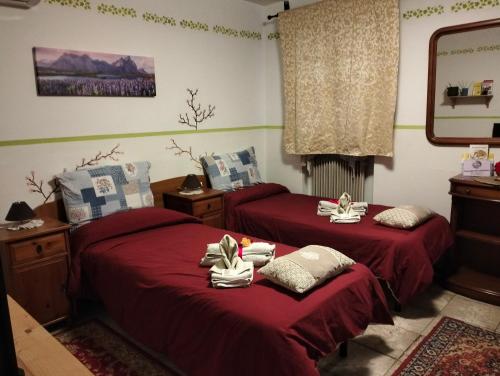 two beds in a room with red sheets at Casa Irene in Torri di Quartesolo