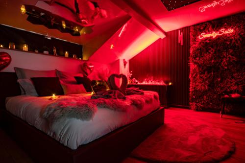 a bedroom with red lighting and a bed in a room at Love Room Serenity Suite in Montbéliard