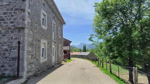 an old stone building with a fence next to a road at Casa Anibal in Burón