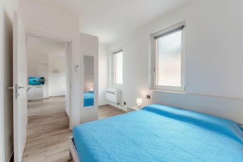 a white bedroom with a blue bed and a window at Lake Como Retreat Menaggio in Menaggio