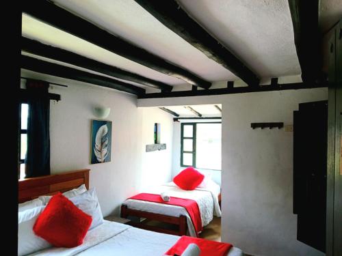 a bedroom with two beds with red pillows on them at La tranquera hotel in Villa de Leyva