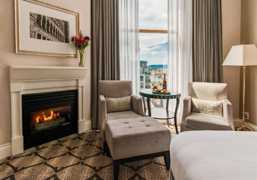 a hotel room with a fireplace and a bed and chairs at The Magnolia Hotel & Spa in Victoria