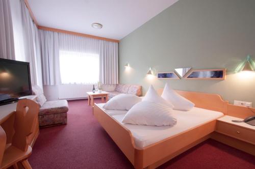 a hotel room with a bed and a television at Hotel Alpenfriede in Jerzens